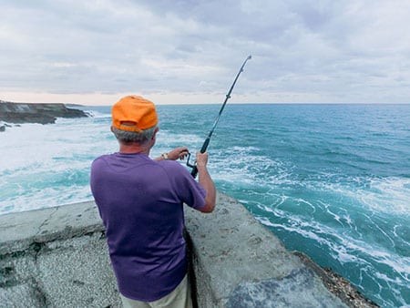 Un homme pêchant depuis le rivage avec une canne à lancer à Ténérife, muni d'un permis de pêche
