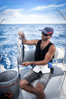 pêcheur ayant capturé un petit thon à la traîne avec un leurre